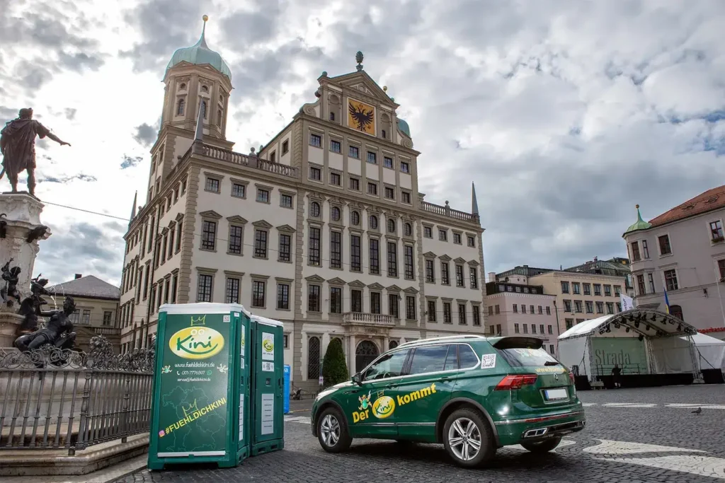 grüne mobile Toilette neben grünem Auto
